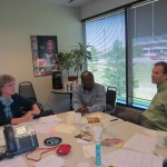 Staff members Steve Nelson (right) and Michael Okleme (center) visit with volunteer Linda.